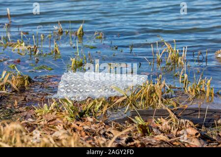 Kunststoff Bubble Wrap floating im blauen Wasser des Sees. Konzept der Wasserverschmutzung, Abfall und Recycling Stockfoto