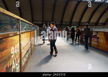 Menschen, die über eine Fußgängerbrücke am Bahnhof York, North Yorkshire, England, Großbritannien, gehen. Stockfoto