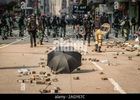 HongKong - November, 2019: umrella auf dem Boden mit Hong Kong Polizei und Demonstranten im Hintergrund, während sie 2019 HongKong Proteste Stockfoto