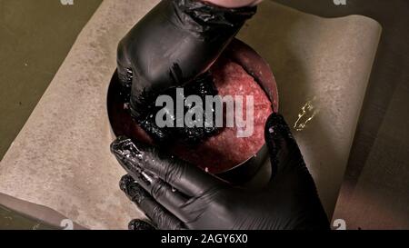 Kochen macht Fleisch Medaillons für Burger. Koch in schwarz Handschuhe macht Schnitzel essen. Die koteletts sind in Stahl Ring in eine noch Medaillon eingeebnet. Stockfoto