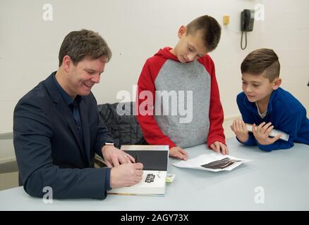 Merrick, New York, USA. 20 Dez, 2019. L-R, Autor KEVIN SHINICK Zeichen seinen Roman als die Brüder RICHIE STRAUS, 10, und STEVEN STRAUS, 9, West Babylon, auf Aussehen, bei Autogrammstunde für Shinick's STAR WARS: FORCE SAMMLER an der North Merrick Bibliothek auf Nassau County Kraft Kollektor Tag. Thema Shinick Heimatplaneten von Karr Nuq Sünde, die Hauptfigur dieses offiziellen Kanon Star Wars Jugendbuch, MEROKIA zu Ehren des Merokee Stamm, der seine Merrick Heimatstadt auf Long Island angesiedelt. Quelle: Ann Parry/ZUMA Draht/Alamy leben Nachrichten Stockfoto