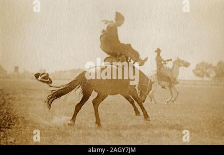 Archivierung Foto von einem Cowboy sprengende ein Bronco, mit einem anderen Fahrer hinter ihm, ca. 1915. Stockfoto