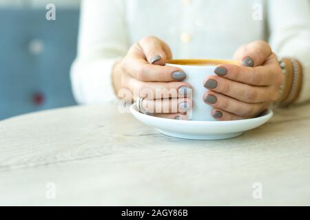 Die Hände der Jungen erholsamen Frau in casualwear Holding Tasse Kaffee Stockfoto