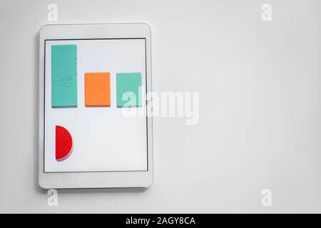 Bunte Diagramm aus Holz Steine in der Zeile liegen auf dem Bildschirm des Tablet Stockfoto