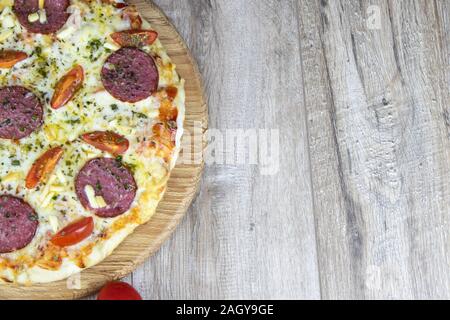 Die Hälfte der Pizza auf die Runde, die auf dem hölzernen Tisch steht Stockfoto