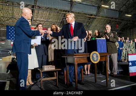 Us-Präsident Donald Trump Hände einen Stift zu Space Force ersten Leiter der Space Operations, General John Raymond, Links, nach einer feierlichen Unterzeichnung für Sl. 1790, das National Defense Authorization Act für das Geschäftsjahr 2020 im Hangar 6 am Andrews Air Force Base Dezember 20, 2019 in Clinton, Maryland. Trump hielt das Ereignis vor der Abreise für zwei Wochen Urlaub zu seinem Resort in Palm Beach. Stockfoto