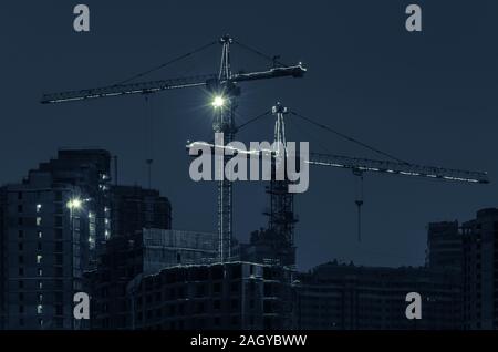 Baukräne mit LED-Beleuchtung an einer Baustelle auf einer Winternacht. Getönten Foto. Stockfoto