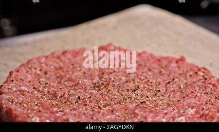 Kochen macht Fleisch Medaillons für Burger. Koch in schwarz Handschuhe macht Schnitzel essen. Die koteletts sind in Stahl Ring in eine noch Medaillon eingeebnet. Stockfoto