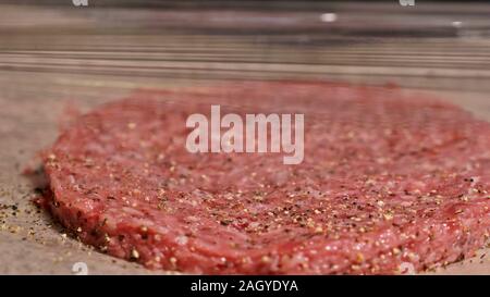 Kochen macht Fleisch Medaillons für Burger. Koch in schwarz Handschuhe macht Schnitzel essen. Die koteletts sind in Stahl Ring in eine noch Medaillon eingeebnet. Stockfoto