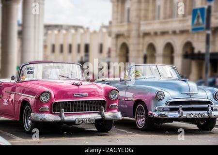 Ein paar Klassiker, Oldtimer aus den 1950er, lackiert hot pink und Türkis, beziehungsweise in der Altstadt von der Stadt Havanna, Kuba geparkt Stockfoto