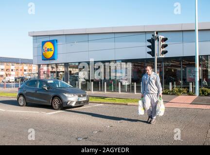 Neu gebaute Lidl in Blackpool verkaufen Kosten cuttring Elemente wie Getränke, Essen etc. Mann mit Shopping bnags Crossing Road. Auf ein papageientaucher Kreuzung. Stockfoto