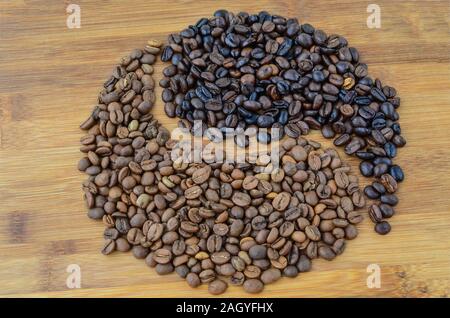 Yin Yang Form von gerösteten und Ungerösteten Kaffeebohnen auf bambus holz- Oberfläche Stockfoto