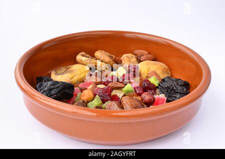 Verschiedene Sorten von getrockneten Früchten in orange Ton Schüssel auf weißem Hintergrund, Seitenansicht Stockfoto