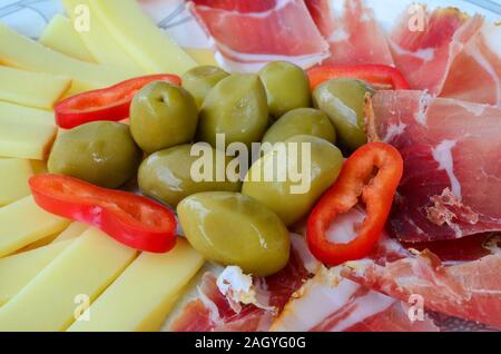 Grüne Oliven mit in Scheiben geschnittenen Schinken, geräucherte Schafskäse und ein paar Stücke von Red Hot peppers Stockfoto