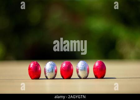 Ein Porträt von Schokolade Ostereier in Zinn bunte foiln aufgewickelt oben stehend auf einem Tisch bereit gefunden und von Kindern auf ihrer Ostereiersuche gegessen werden. Stockfoto