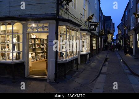 Geschäfte auf dem mittelalterlichen Trümmern Straße im Zentrum von York in der Dämmerung, York, Großbritannien Stockfoto