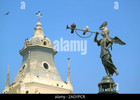Historische Statue der Engel des Ruhmes auf dem Brunnen am Plaza Mayor in Lima mit entspannenden Tauben und verschwommen Kathedrale Wachturm im Hintergrund, Peru Stockfoto