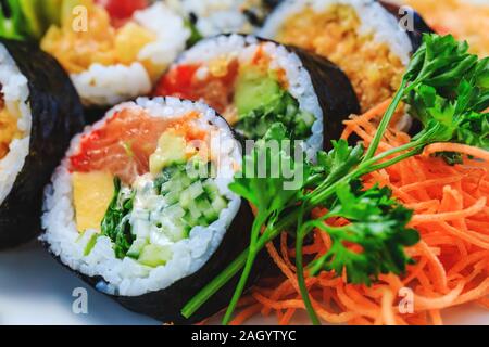 Abwechslungsreiche Sushi mit Gurke Maki, Koreanisch Karotte, Petersilie, Meer Kohl und Lachs Maki. Japanischen sashimi Sushi Brötchen mit Lachs Rogen in Nahaufnahme Bild Stockfoto