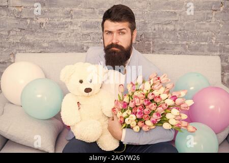 Mann gut gepflegt Verschleiß tuxedo Bow Tie halten Blumen Tulpen Bouquet und großen Teddybären Spielzeug. Laden Sie dating. Romantisches Geschenk. Romantischen Mann. Macho fertig, romantisches Date. Warten auf Darling. Stockfoto