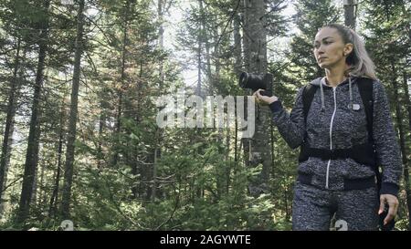 Traveler fotografieren malerischen Blick in den Wald. Eine kaukasische Frau schießen nettes Magic suchen. Mädchen nehmen Foto Video auf dslr spiegellosen Kamera. Stockfoto