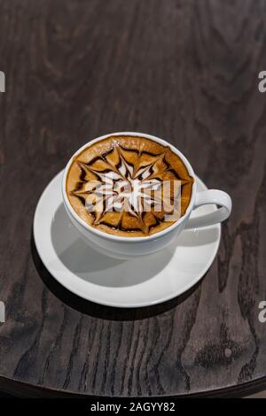 Vertikale Foto von Latte Art Kaffeetasse auf hölzernen Tisch Stockfoto