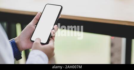 7/8 shot der jungen Geschäftsfrau mit leeren Bildschirm Smartphone außerhalb der Zimmer Stockfoto
