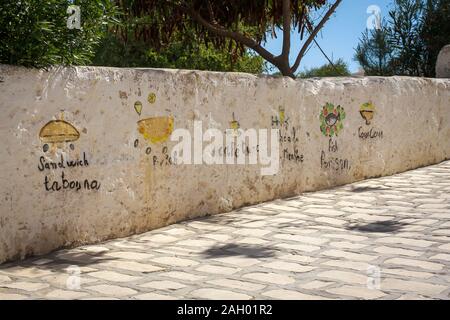 Handbemalte Speisekarte des nahe gelegenen Restaurants, die an der Wand in Hergla, Tunesien, gemalt ist Stockfoto