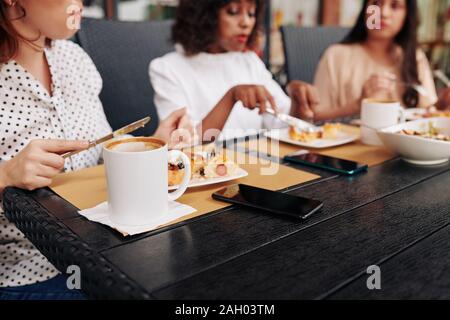 Weiblichen Mitarbeitern am großen Tisch sitzen im Café und aßen zu Mittag zusammen Stockfoto