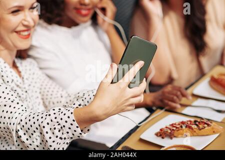 Lachend glückliche junge Frau fotografieren mit Freunden auf dem Smartphone wenn Sie sind ein Mittagessen im Cafe Stockfoto