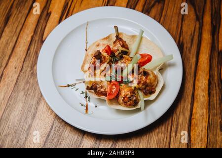 Flügel im Honig - Senf Soße auf knusprige Tortilla mit Gemüse und Kräutern. Stockfoto