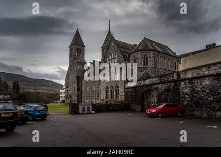 FORT AUGUSTUS, Schottland, 17. Dezember 2018: Die Abtei Highland Club, voller Schimmel und Flechten in seinen Steinmauern, unter starkem cloudscape mit Bergen Stockfoto