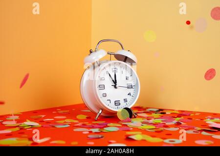 Festliche bunte Konfetti auf einem weißen Wecker fallen. Trendy dreidimensionalen Hintergrund in Pastellfarben. Stockfoto