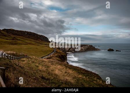 Menschen zu Fuß entlang der Küste weg während eines regnerischen, kalten und trüben Tag auf den Klippen in der Nähe von ballintoy in Nordirland. Stockfoto