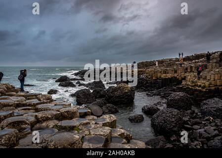 Menschen zu Fuß über die Natur der sechseckige Steine an der Küste namens Giant's Causeway, ein Wahrzeichen in Nordirland. Stockfoto