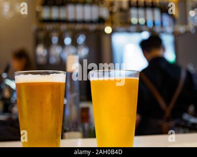 Nahaufnahme von zwei Pints Bier/Lager/ale im Pint Gläser an der Bar Tresen in einem Pub mit bokeh Hintergrund Stockfoto