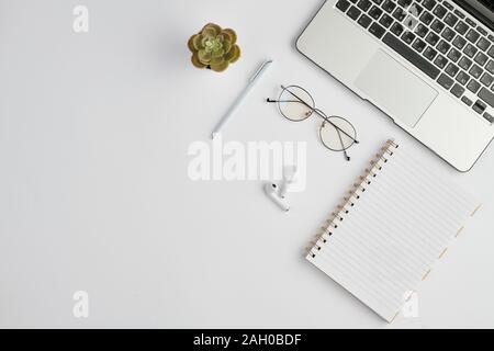 Ohrhörer, Brillen, Kugelschreiber, Notebook, kleine heimische Pflanze und Laptop Tastatur Stockfoto