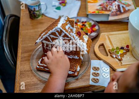 Nicht identifizierbare Kind Junge Haus backen und dekorieren ein Lebkuchen Haus Stockfoto