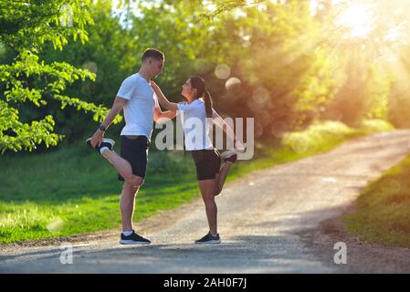 Junges Paar stretching Beine auf einer Straße am Park Stockfoto