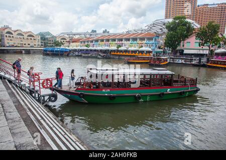 Touristen, die am Clarke Quay auf ein Bum-Boot steigen, um ihre Besichtigungstour entlang des Singapore River zu Unternehmen. Stockfoto