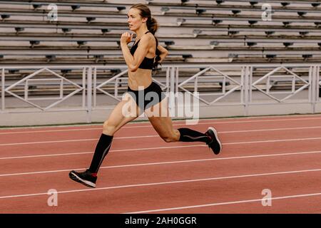 Junge weibliche Athleten in Kompression Socken, die auf Spur Stadion Stockfoto