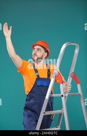 Kaukasische männliche Arbeiter stehen auf tragbare Leiter versuchen, etwas zu erreichen, Studio Portrait Stockfoto