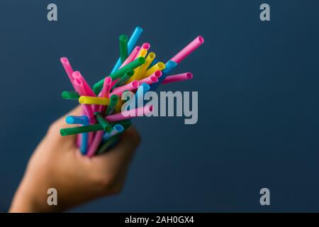 Nahaufnahme einer Hand, die Bambus Strohhalme auf blauem Hintergrund Stockfoto