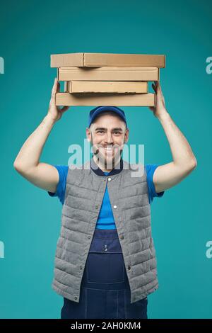 Vertikale studio Portrait von fröhlichen Essen boten Holding Pizzakartons über seinem Kopf an Kamera schaut lächelnd Stockfoto