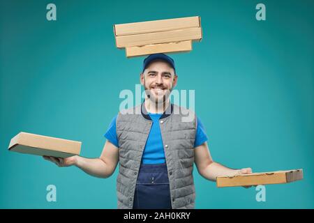 Horizontale medium Studio geschossen von Lustig essen Lieferung Arbeiter mit pizza Schachteln auf dem Kopf und in den Händen stehend gegen blau türkis Hintergrund Stockfoto