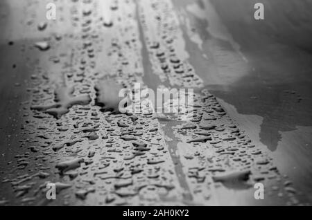 Reines metall Regentropfen. Nahaufnahme von Regentropfen und Spray von Regen auf einem Metalltisch. Augenhöhe schießen. Selektive konzentrieren. Schwarz und Weiß Foto Stockfoto