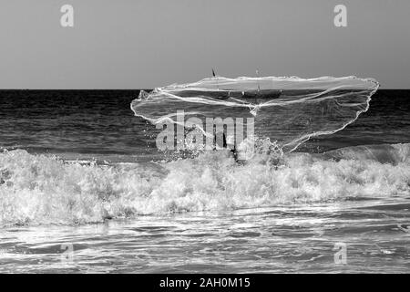 Ein einheimischer Fischer wirft sein Netz in den warmen Gewässern der Bucht von Bengalen. Ngapali Beach, Rakhine, Myanmar Stockfoto