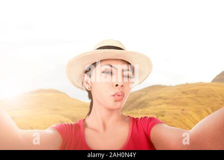 Asiatische Mädchen in hat einen selfie mit einem lustigen mit der Kamera Handy mit Sonnenlicht Hintergrund Gesicht Stockfoto