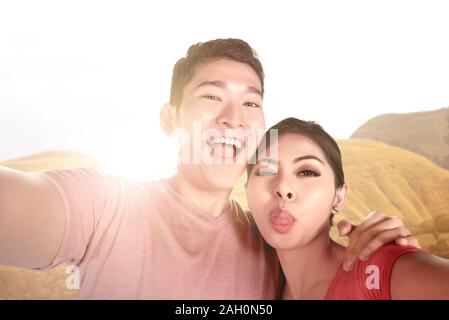 Asiatische Paare einen selfie mit einem lustigen mit einem Fotohandy mit Sonnenlicht Hintergrund Gesicht Stockfoto