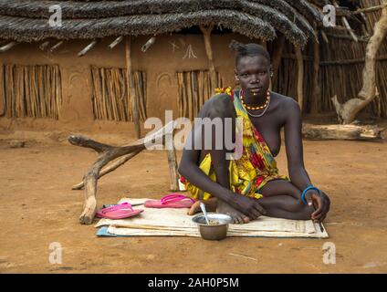 Porträt einer Larim Stamm Frau Essen vor ihrem Haus, Boya Berge, Imatong, South Sudan Stockfoto