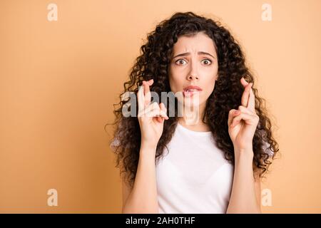 Nahaufnahme der erstaunlichen wellig Dame mit gekreuzten Fingern fragen Glauben glücklichen Sieg beißen Lippen nervös Verschleiß casual Outfit beige Pastell isoliert Stockfoto